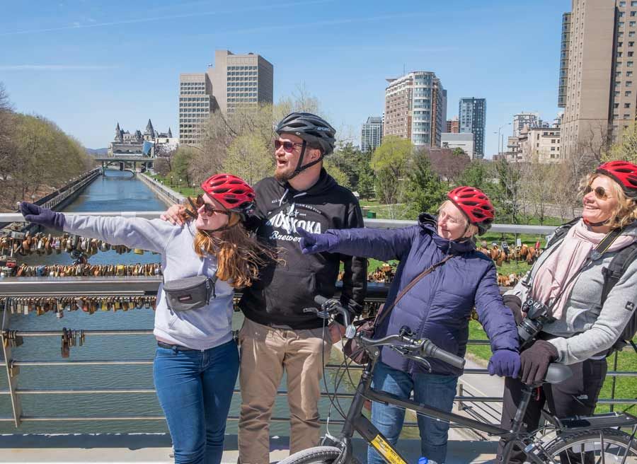 Tour guests are pointing out to a landmark at Love Lock Corktown Bridge at Rideau Canal during Ottawa highlights bike tour