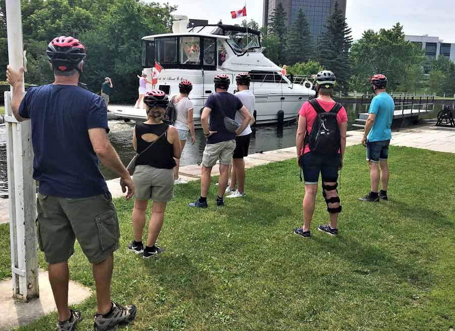 Guests watching the boats crossing Rideau Canal locks during bike & boat bike tours of Ottawa with escape on Sparks st.
