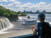 A participant is looking at boat cruise getting close to Rideau Falls Ottawa landmark during bike & boat tour with Escape