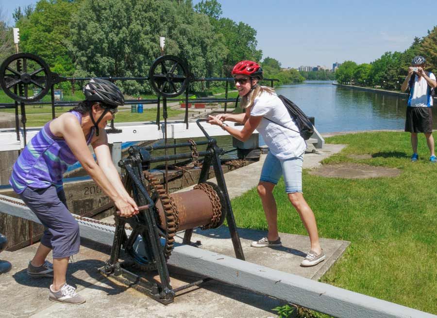 Tour participants are playing with Rideau Canal lock crank at Rideau Canal pathway during Ottawa highlights tour by bike 
