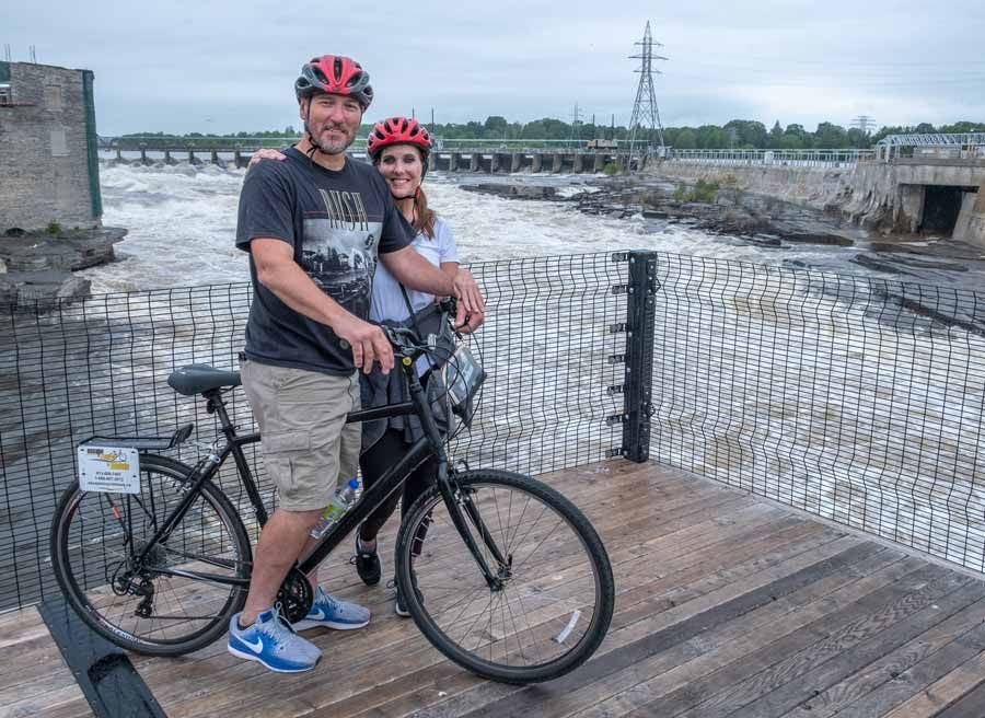 A couple are enjoying the view of Chaudiere Falls during Ottawa multi-day bike tour by Escape tours rentals on Sparks