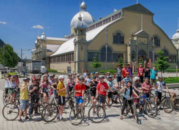 A group of students taking an Ottawa bike tour with Escape and stop at Lansdowne park landmark for rest and sightseeing