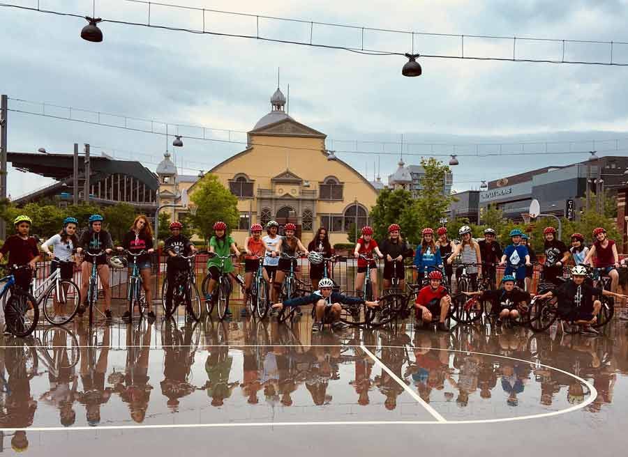 Students taking an Ottawa bike tour with Escape and stop at Lansdowne park landmark and Glebe neighbourhood for sightseeing