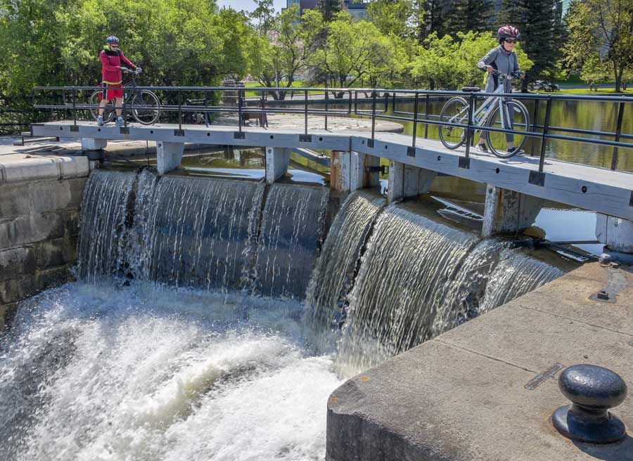 Guests are crossing Rideau Canal Hartwell lock with their bikes during during best of Ottawa Neighbourhood and nature bike tour