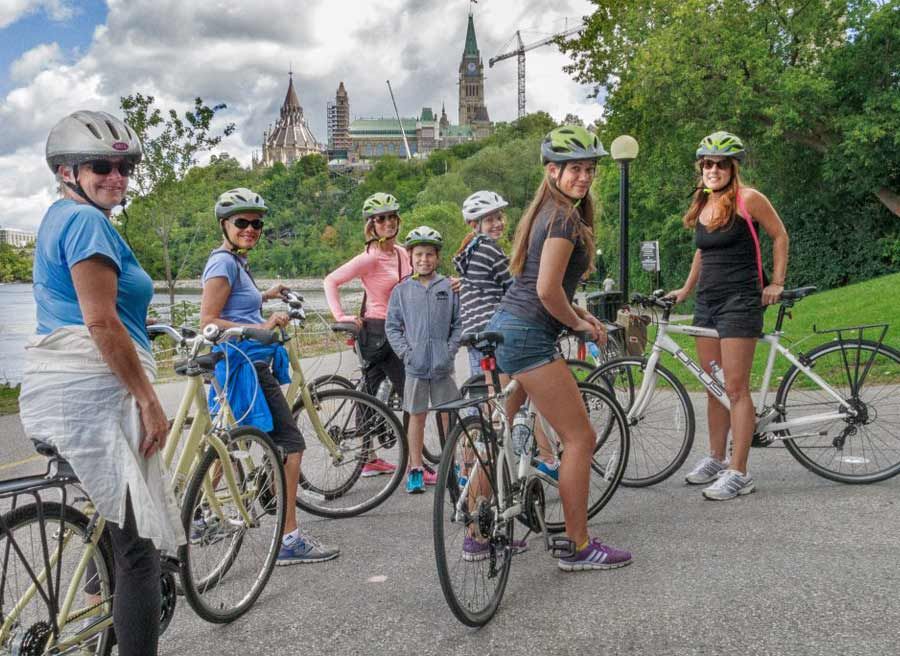 Guests have stopped at Rideau Canal with a view of the Parliament Building during Escape Ottawa express guided bike tour in Ottawa