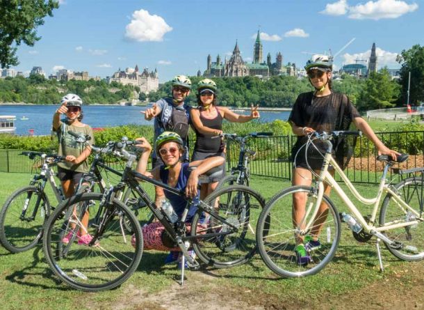 Family enjoying Ottawa express bike tour with a view of the Parliament Building landmark from Ottawa bike trails with escape tours rentals