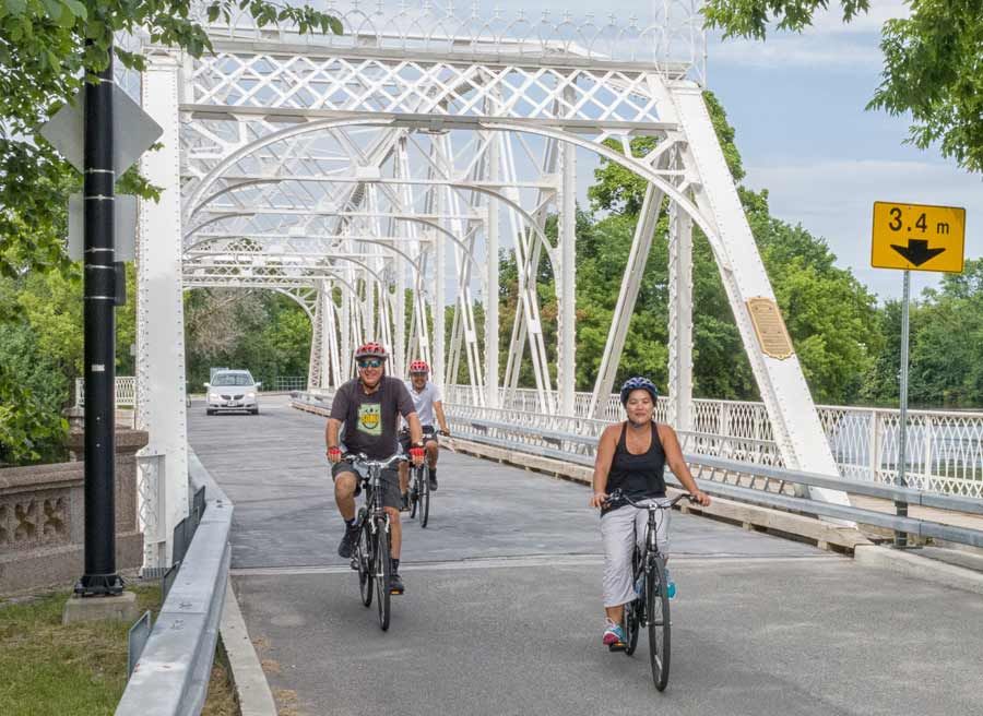 Tour participants are smiling & cycling on Minto bridge in new Edinburgh neighbourhood during best of Ottawa bike tour