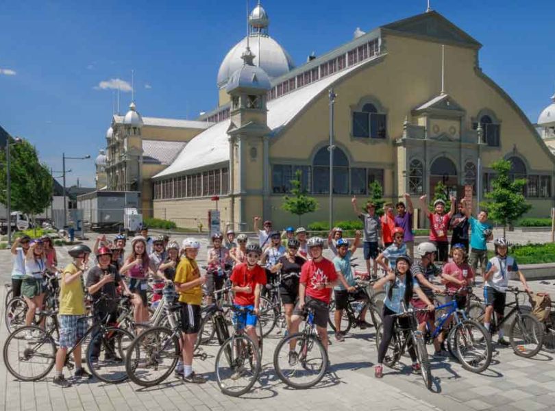 A group of students taking an Ottawa bike tour with Escape and stop at Lansdowne park landmark for rest and sightseeing