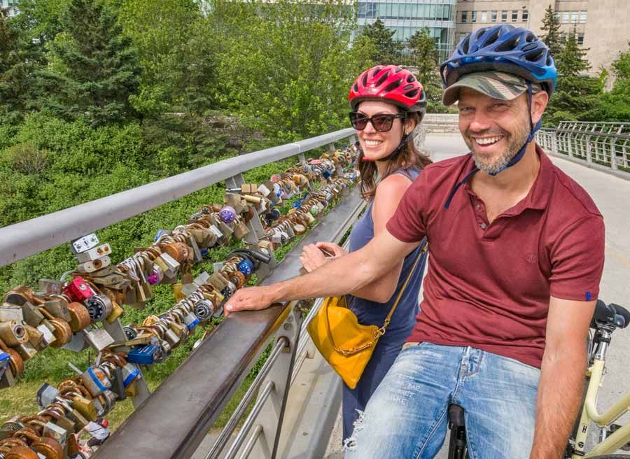 A couple are visiting Love Lock Bridge or Corktown Bridge Landmark at Rideau Canal during Escape Ottawa Express Bike tour with Escape