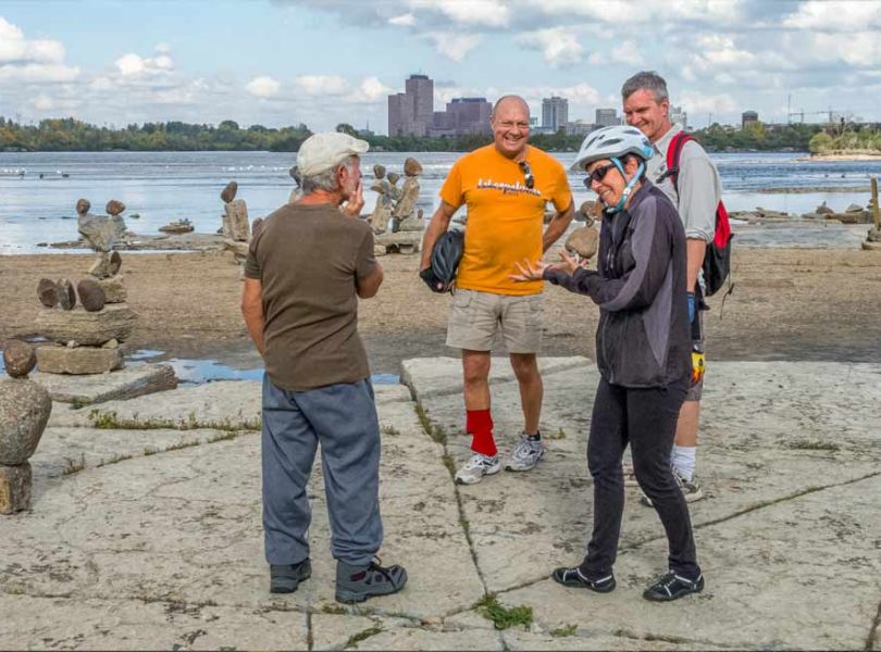 Participants stop at Remic Rapids Park and chat with John Ceprano about rock sculptures during their Best of Ottawa Bike Tour with Escape