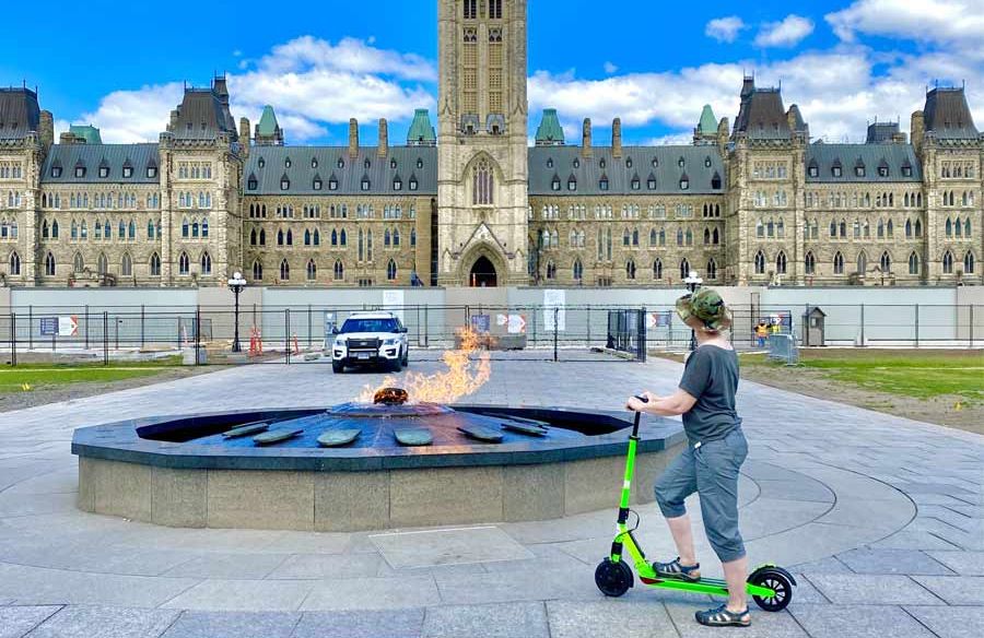 A customer is riding e scooter rental to parliament hill and looking at Centennial Flame with rental from Escape on Sparks st. Ottawa