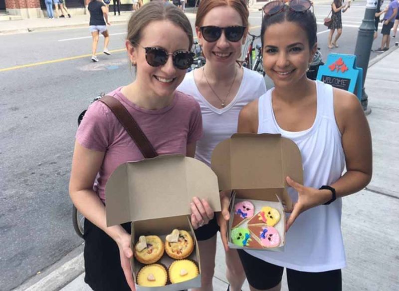 Young women show their delicious takeout cookies from 3 Tarts in Centretown during bike and food tour of Ottawa with Escape