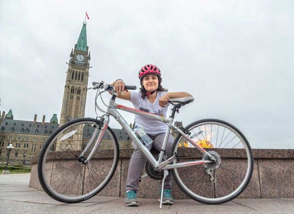 Escape Bicycle tours & Rentals’ Founder, Maria sitting at the edge of Centennial Flame at Parliament Hill with Peace tower view