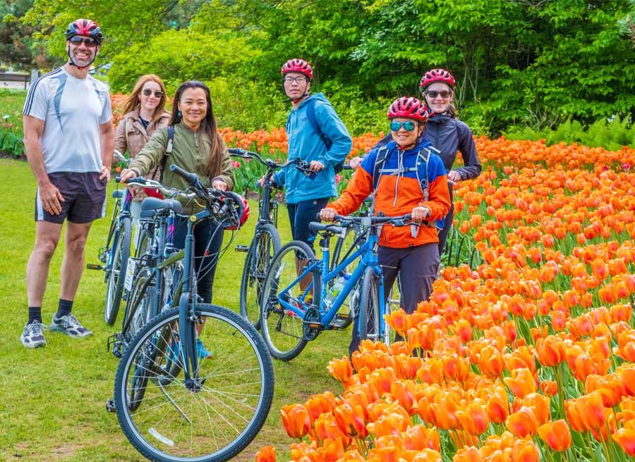 Tulip bike tour guests taking a group picture in front of orange tulips during Tulip festival at Commissioners park in May