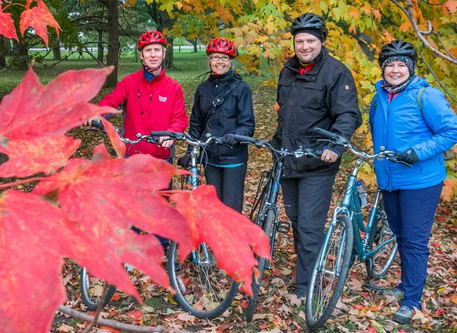 Guests looking at red Fall colours and taking pictures in Ottawa park during Ottawa highlights bike tour by Escape 