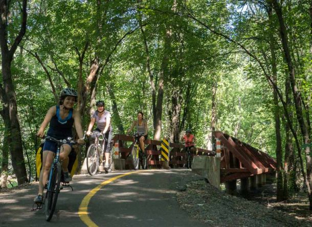 Group cycling at Voyageur bike trails on a sunny day from Ottawa to Aylmer and crossing an iconic wooden bridge with Escape Tours Rentals