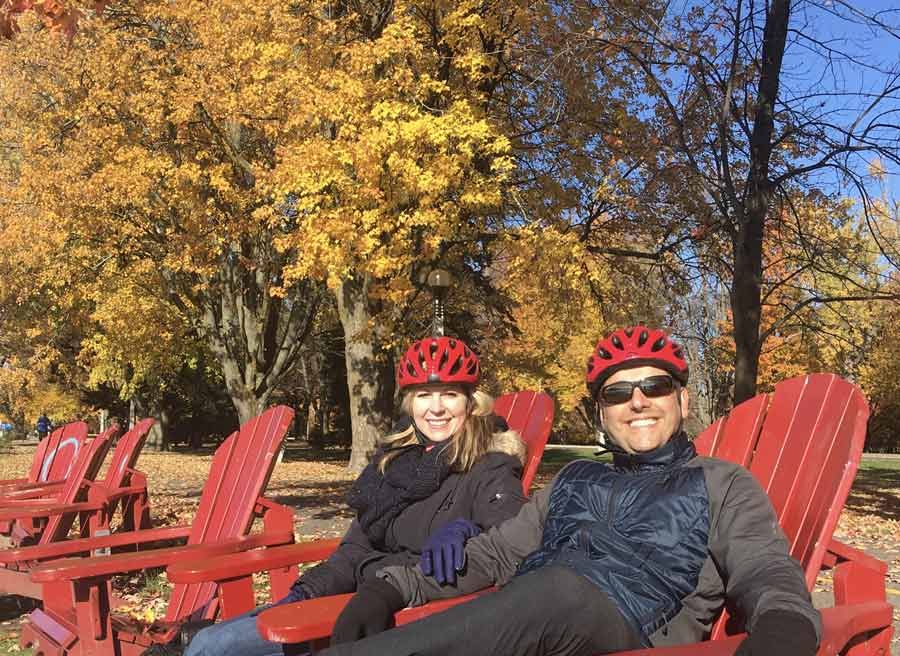 A couple is relaxing at adirondack chairs in a park during their bike and spa tour in ottawa with Escape tours and rentals 
