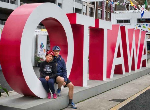 Couple taking a picture next to the Ottawa sign at the Byward market during multi-day bike tour of Ottawa with Escape