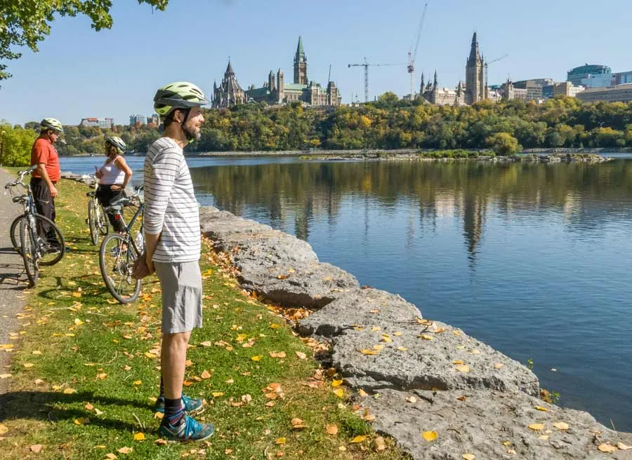 Guests have stopped at bike trail to take picture of Ottawa River and Parliament Building during Best of Ottawa bike tour