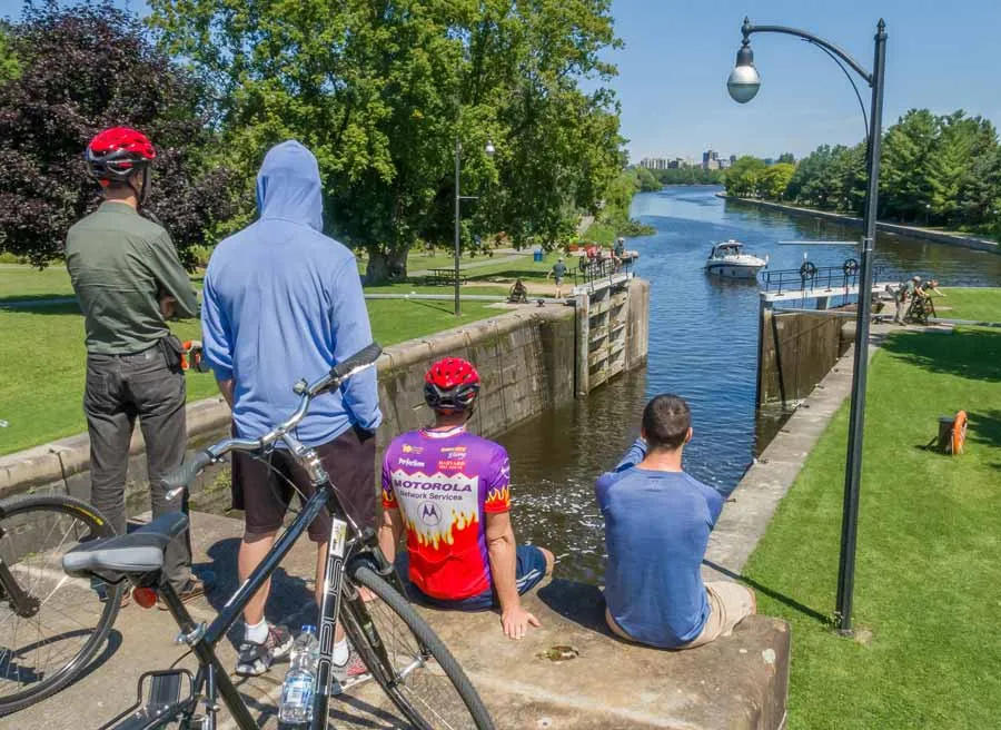 Participants sitting at a bench watching boats crossing Hartwells lock at Rideau Canal during best Ottawa bike tour by Escape