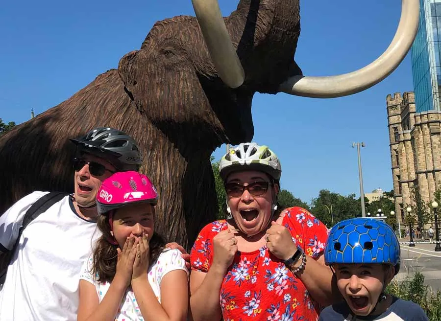 Family visit elephant sculptures in front of the Museum of nature during their bike and food tour of Ottawa with Escape
