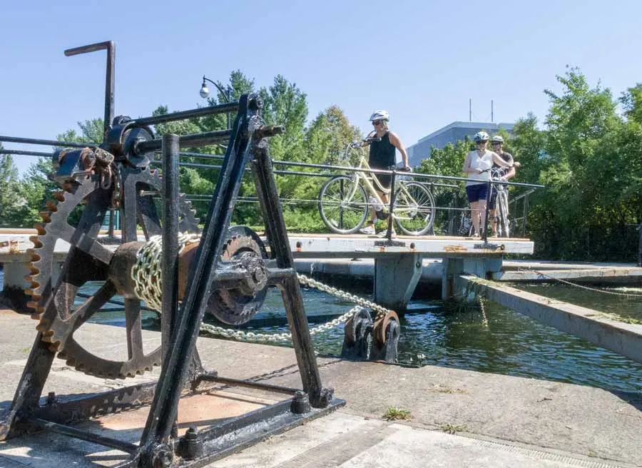 Guests are crossing Rideau Canal lock with their bikes during during best of Ottawa Neighbourhood and nature bike tour 