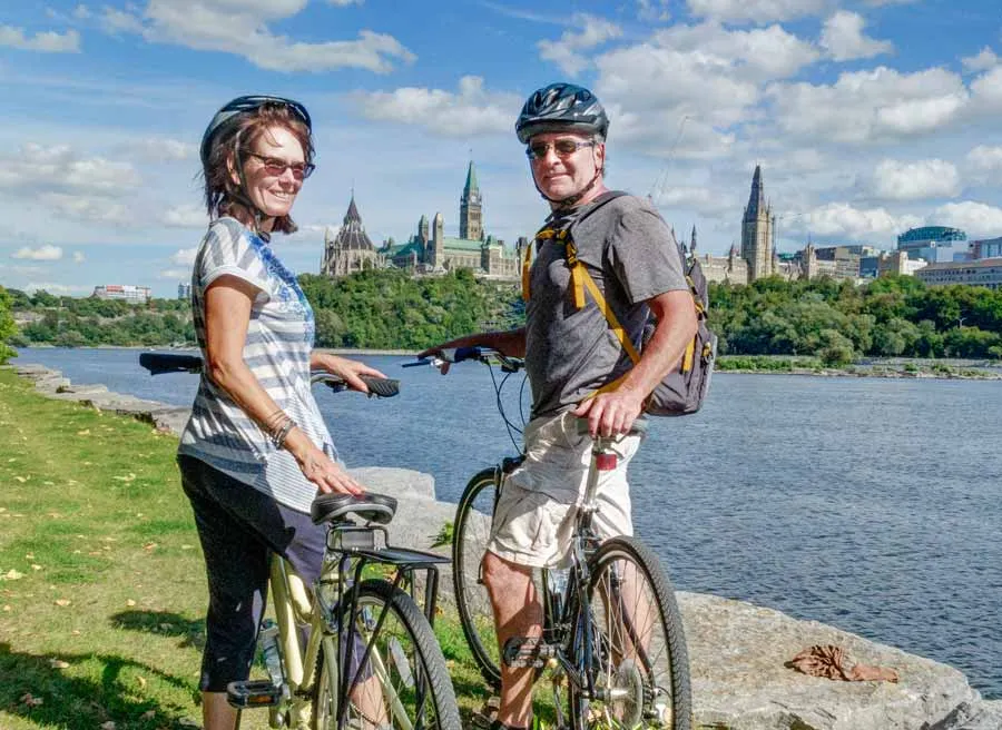 Guests stop at bike path to take pictures of Ottawa River and Parliament Building during a private Ottawa bike tour with Escape Tours Rentals