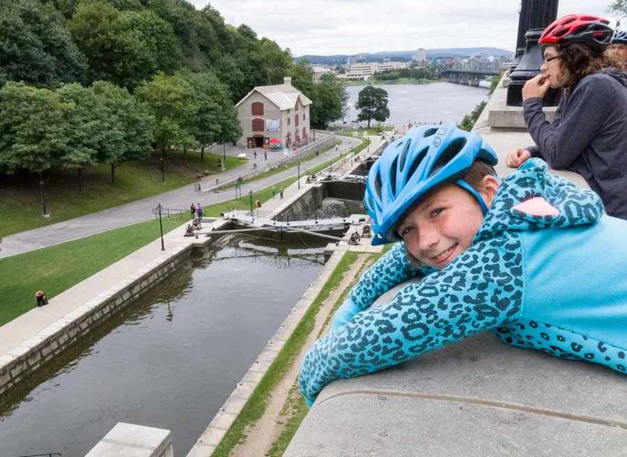 A kid is watching Rideau Canal locks from Fairmont Chateau Laurier look out during Ottawa express bike tour by Escape