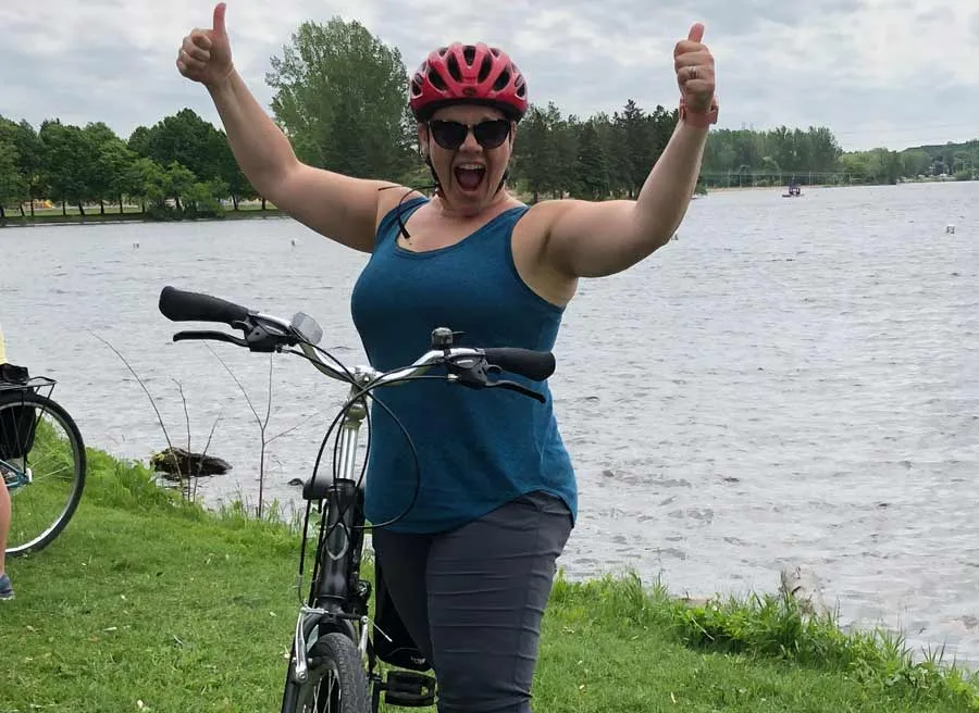 A woman is happy and giving 2 thumbs up to Escape Tours and rentals during her bike tour in Ottawa at Ottawa river pathway