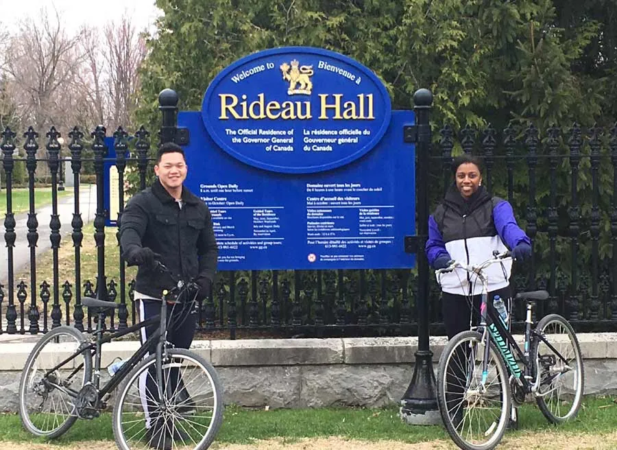 Tour guide is taking  a picture of a couple in front of Rideau Hall during Ottawa express guided bike tour with Escape