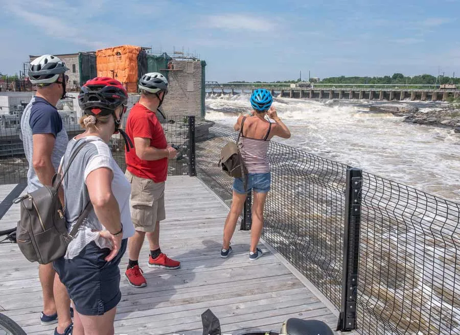 Tour participants are enjoying the view and taking picture of Chaudiere Falls during Ottawa highlights bike tour by Escape