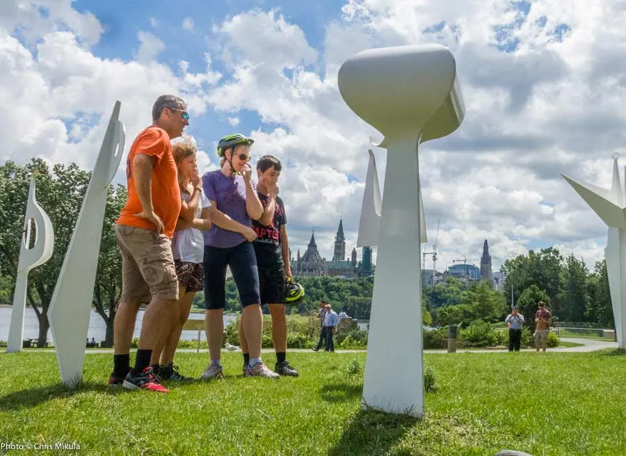 Guests are looking at and learning about art sculptures in front of Museum of History during Ottawa highlights bike tour
