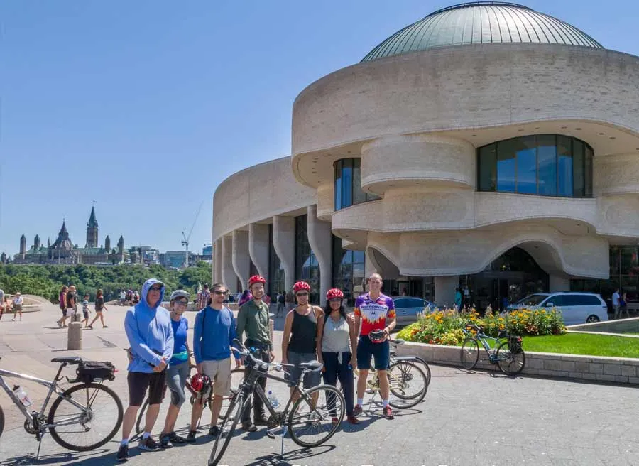 Tour participants taking a picture at the Museum of History lookout with Parliament view during Ottawa highlights bike tour