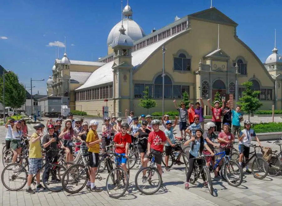 A group of students taking an Ottawa bike tour with Escape and stop at Lansdowne park landmark for rest and sightseeing