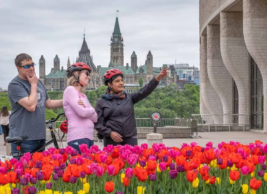 A family is taking a picture at the museum of History lookout with a the parliament view during their private Best of Ottawa bike tour with Escape