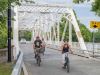 Tour participants are smiling & cycling on Minto bridge in new Edinburgh neighbourhood during best of Ottawa bike tour