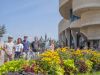 A small- group of tour guests taking a picture in front of a flower garden at History museum during Escape garden bike tour