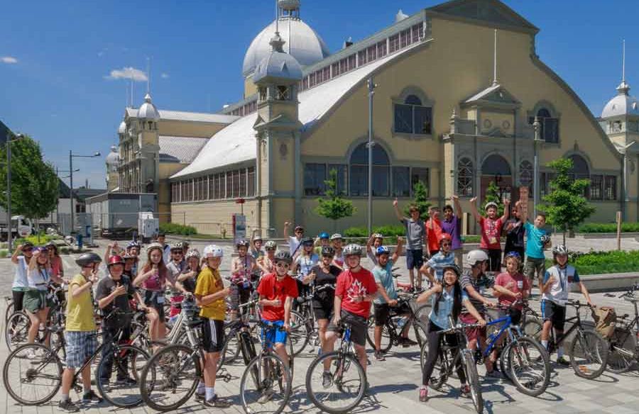 A group of students taking an Ottawa bike tour with Escape and stop at Lansdowne park landmark for rest and sightseeing