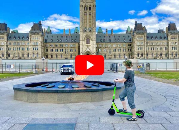 A customer is visiting parliament hill and looking at Centennial Flame with escooter rental from Escape on Sparks st. Ottawa